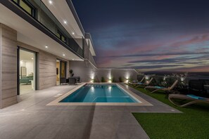 A modern outdoor pool area with a view of the city skyline at dusk. - Villa Adriatique Solina Zadarvillas (Jasenice)