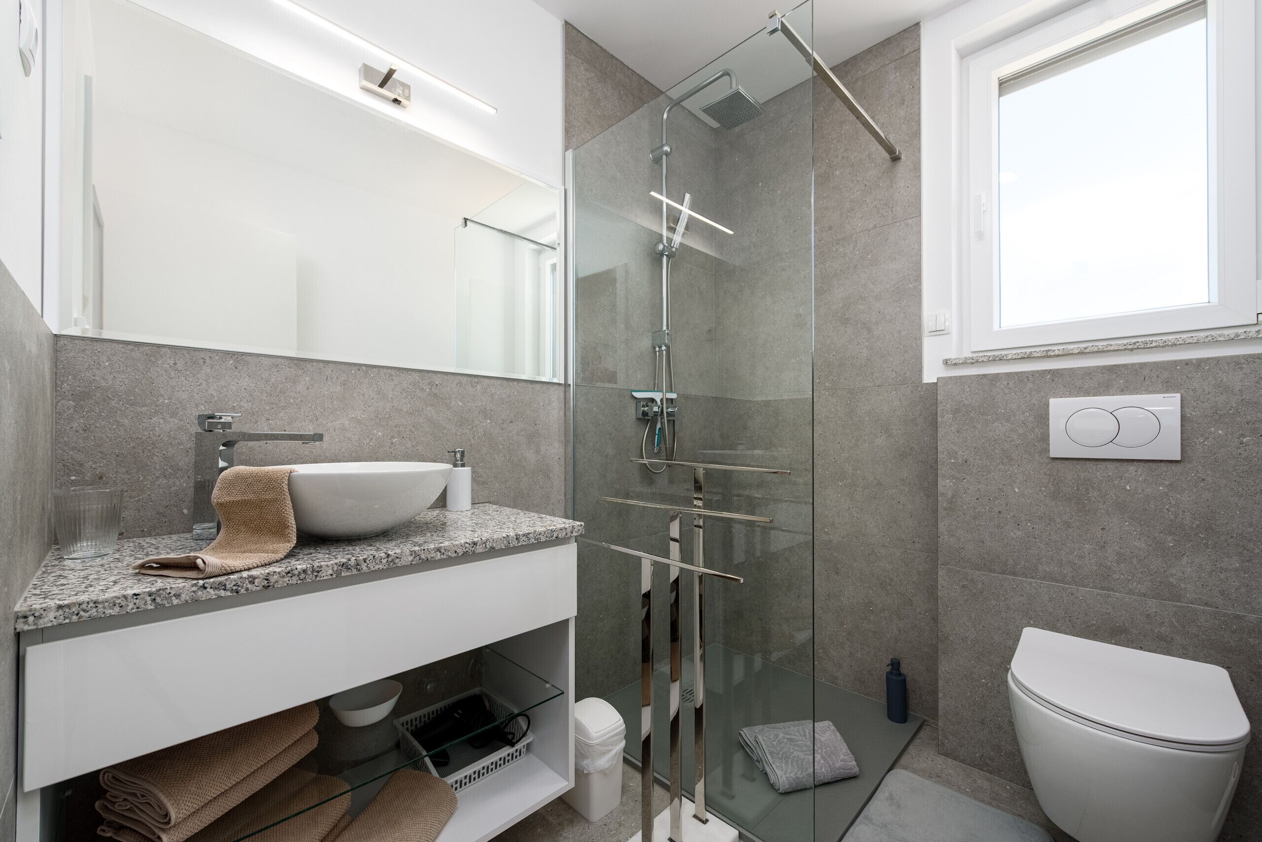 Une salle de bain moderne avec une douche à parois de verre, un lavabo blanc et des toilettes.