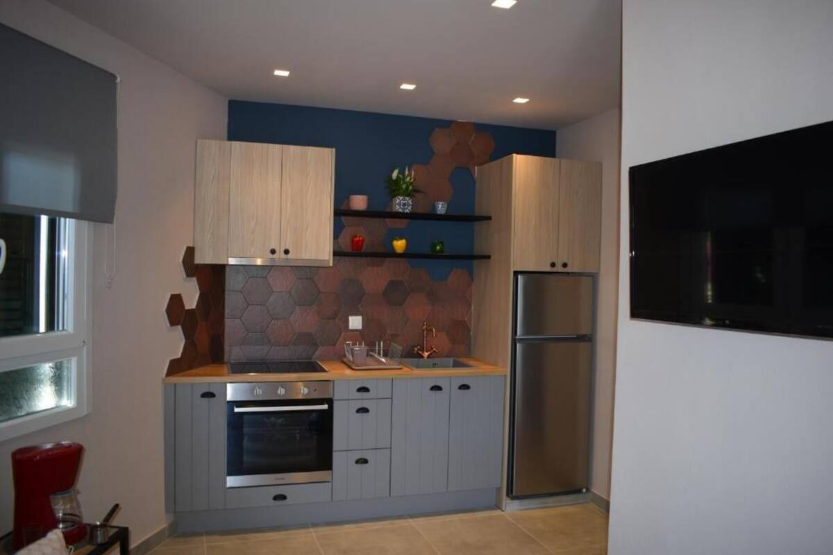 Une cuisine moderne avec des armoires en bois, un four encastré, un réfrigérateur en acier inoxydable et un mur d’accent bleu.