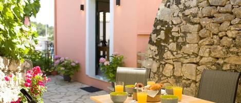 A table set with breakfast items, a stone wall, and a door leading to a room.