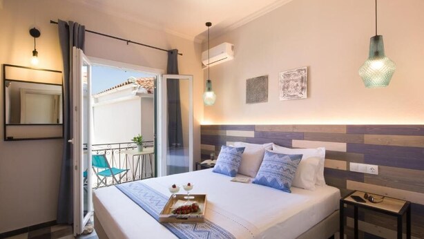 Habitación de hotel con cama, mesita de noche y balcón con una silla.