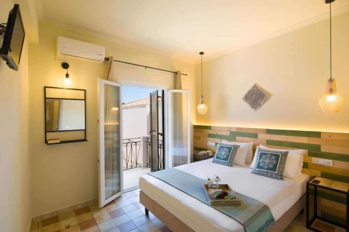 Une chambre d’hôtel équipée d’un lit, d’une télévision, d’un climatiseur, d’un balcon et d’un luminaire fixé au mur.