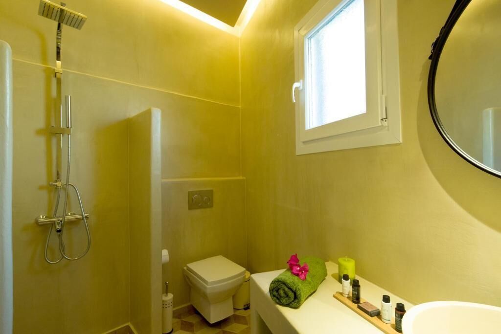 A bathroom with a shower, toilet, sink, and a window.