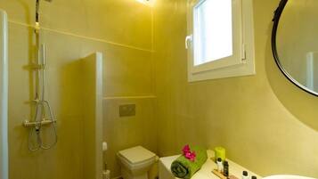 A bathroom with a shower, toilet, sink, and a window.