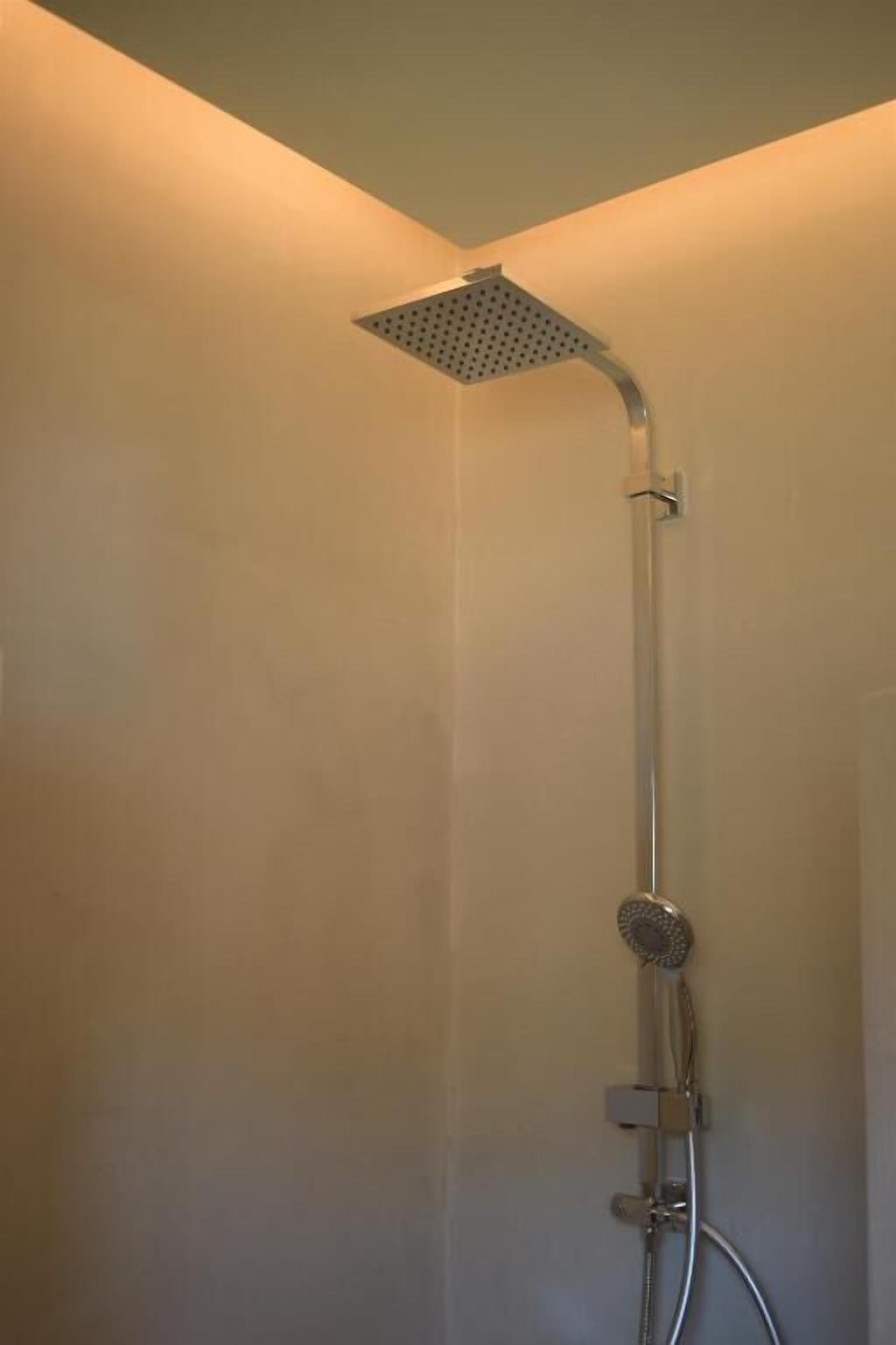 A shower with a square head, a handheld showerhead, and a handheld hose.