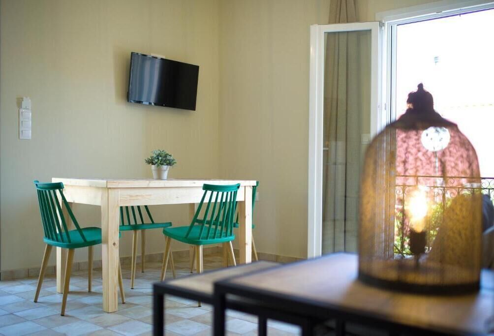 A dining area with a table and chairs, a television on the wall, and a window with a view.