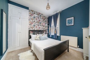 A bedroom with a bed, a wardrobe, a radiator, and a window with curtains. - Stunning 2 Bedroom Apart| Private Garden | Fulham (Greater London)