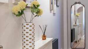 Ein Flur mit einer weißen Kommode, einem Spiegel und einer Blumenvase.