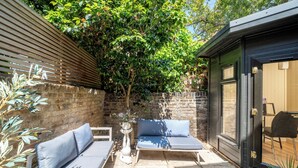 Eine Terrasse mit zwei Sofas, einem kleinen Tisch und einer Tür zu einem überdachten Bereich.