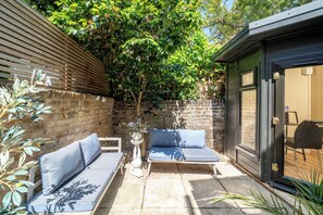 Un patio con dos sofás, una mesa pequeña y una puerta a una zona cubierta.