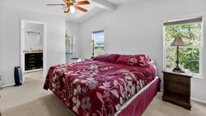 Ein Schlafzimmer mit Bett, Deckenventilator, Fenster mit Aussicht, Nachttisch und Kommode.