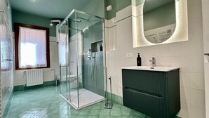 Un baño moderno con cabina de ducha de vidrio, lavabo con espejo y radiador.