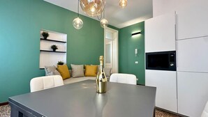 Una cocina moderna con una isla central, armarios blancos, un microondas y una pared de acento verde.