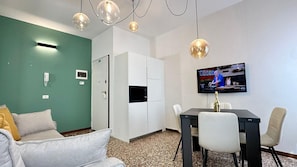 A room with a green wall, a white wardrobe, a TV on the wall, a dining table with chairs, and a sofa. - Santa Marina Bis (Historical Center) (Venice)