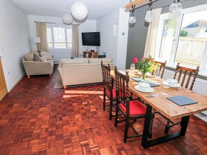 Ein Essbereich mit Holztisch, Stühlen und einem Fernseher im Hintergrund.
