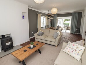 Ein Wohnzimmer mit einer Couch, einem Holztisch, einem Kamin und einem Essbereich mit Tisch und Stühlen.