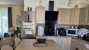 A modern kitchen with a central island, wooden cabinets, a built-in microwave, and a hanging light fixture. - Le Clos Carion A little corner of paradise just a stone's throw from the town center (Autun)