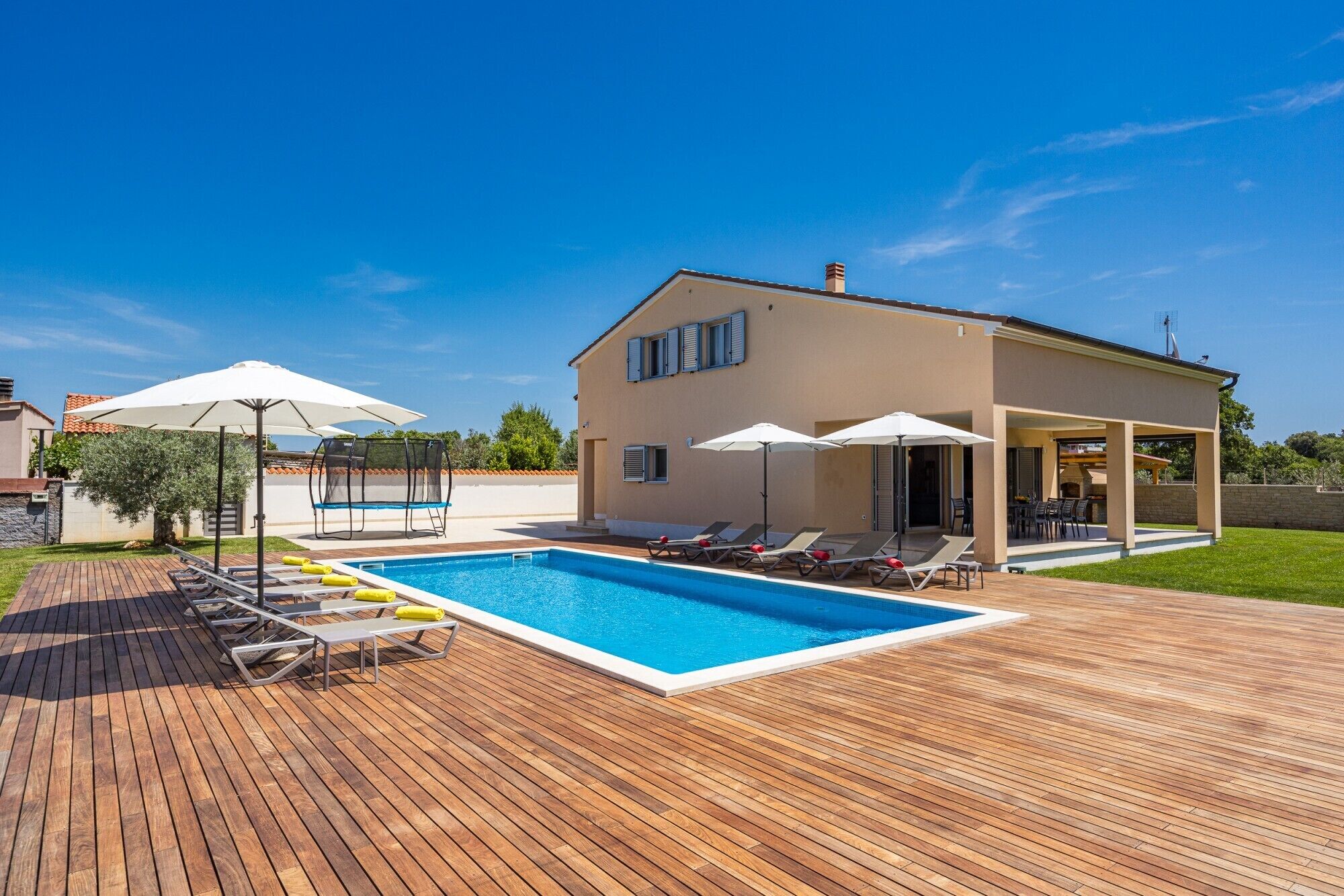 A modern house with a swimming pool, outdoor seating, and a covered patio area.