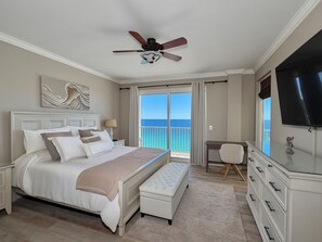 A bedroom with a bed, a desk, a television, and a balcony with a view of the ocean. - Luxurious & Private, Beach Front, Pool, 3BD/2BA, 1800 SqFt, Large Balcony (Panama City Beach)