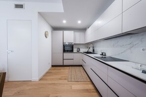 Eine moderne Küche mit weißen Schränken, Holzboden und einem eingebauten Backofen.