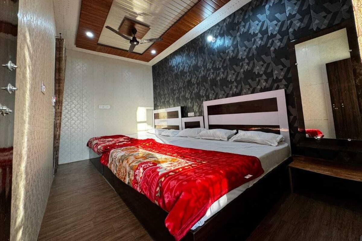 A bedroom with a large bed, a ceiling fan, a wooden ceiling, and a patterned wall.