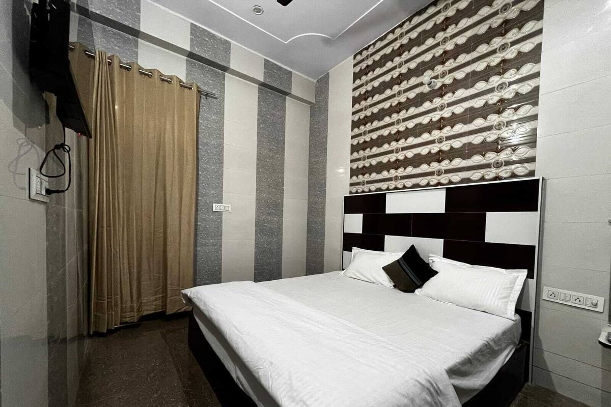 A bedroom with a bed, curtains, a headboard, and a wall with a decorative pattern.