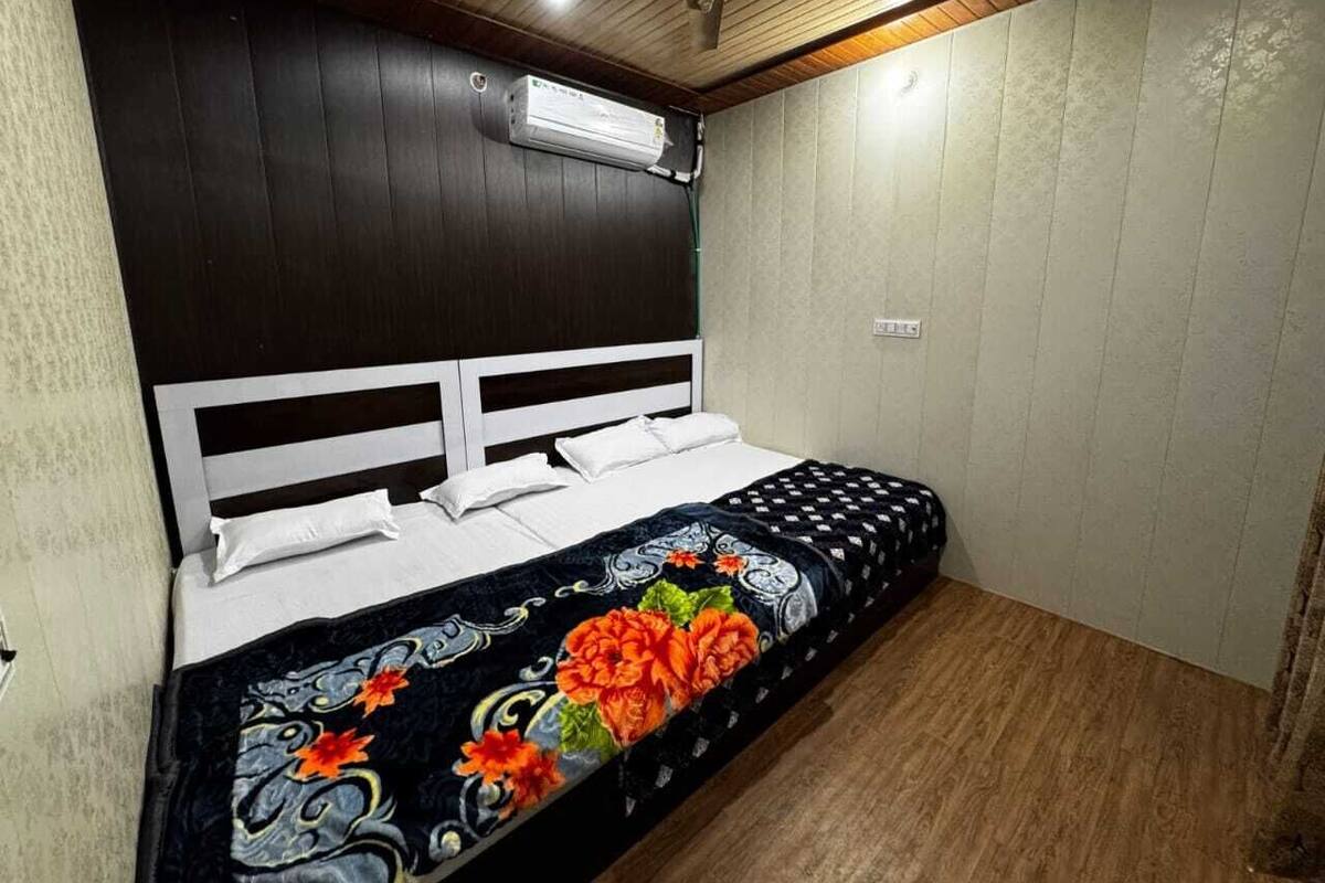 A bedroom with a bed, white headboard, and a floral bedspread.