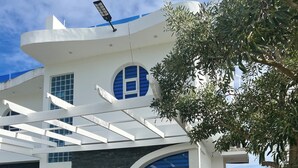 Un edificio moderno con un diseño arquitectónico único, que presenta una amplia entrada en arco, un corredor cubierto y un jardín bien cuidado.