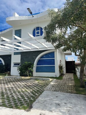A modern building with a unique architectural design, featuring a large arched entrance, a covered walkway, and a well-maintained garden area. - Tranquil Villa with Private Pool in Punta Cana (Punta Cana)