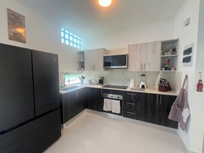 A modern kitchen with a black refrigerator, a microwave, a sink, and a window with blinds. - Tranquil Villa with Private Pool in Punta Cana (Punta Cana)