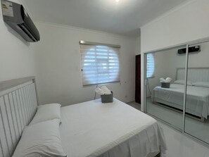 A bedroom with a bed, a window with blinds, a mirror, and an air conditioning unit. - Tranquil Villa with Private Pool in Punta Cana (Punta Cana)
