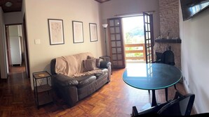 A living room with a sofa, a glass table, and a view of the outdoors. - Apartment in the Tourist Center with 24-hour Reception/Concierge (Campos do Jordão)
