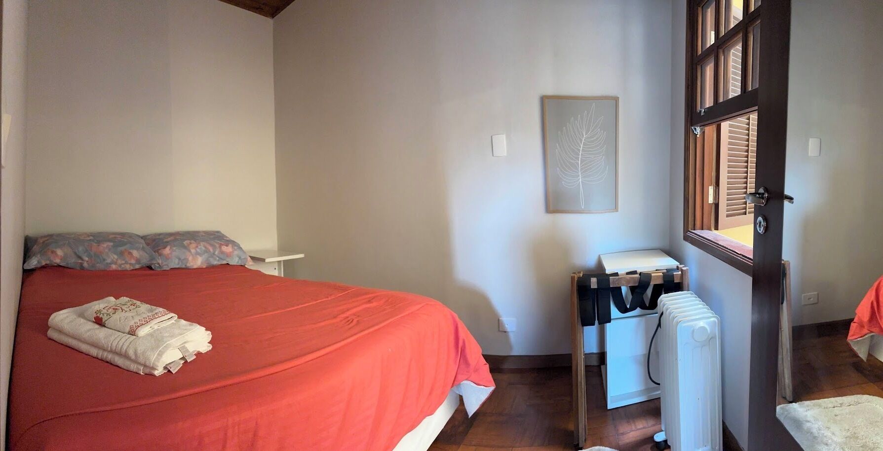 A bedroom with a bed, a radiator, a window, and a door.