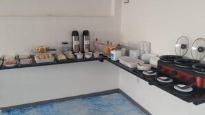 Ett kök med en svart bänkskiva, diverse livsmedel, en kaffebryggare och en röd spis.
