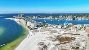 Ett flygbildsbild av en kuststad med en strand, en småbåtshamn och byggnader.