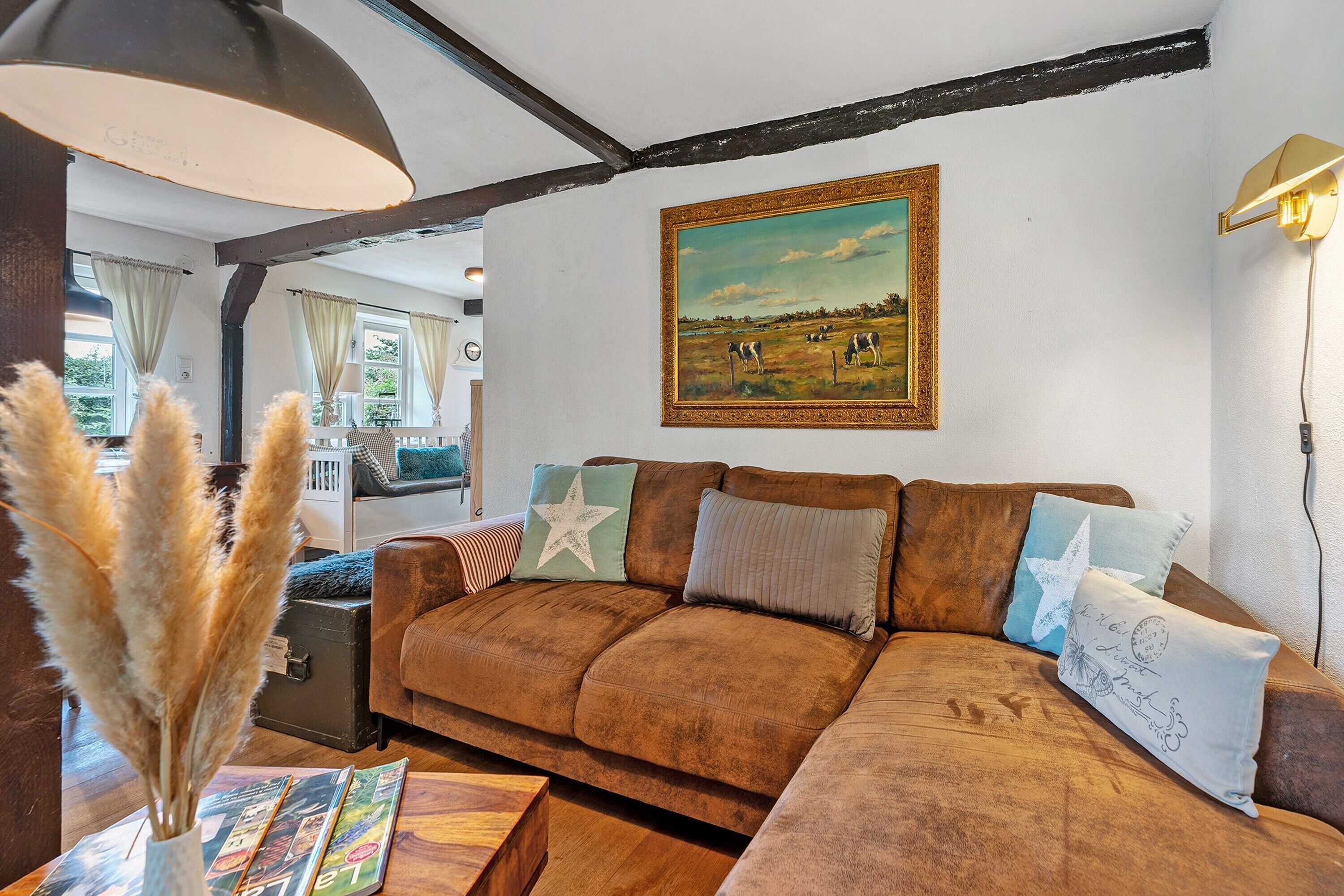 Een woonkamer met een bruine bank, een schilderij en een lamp.