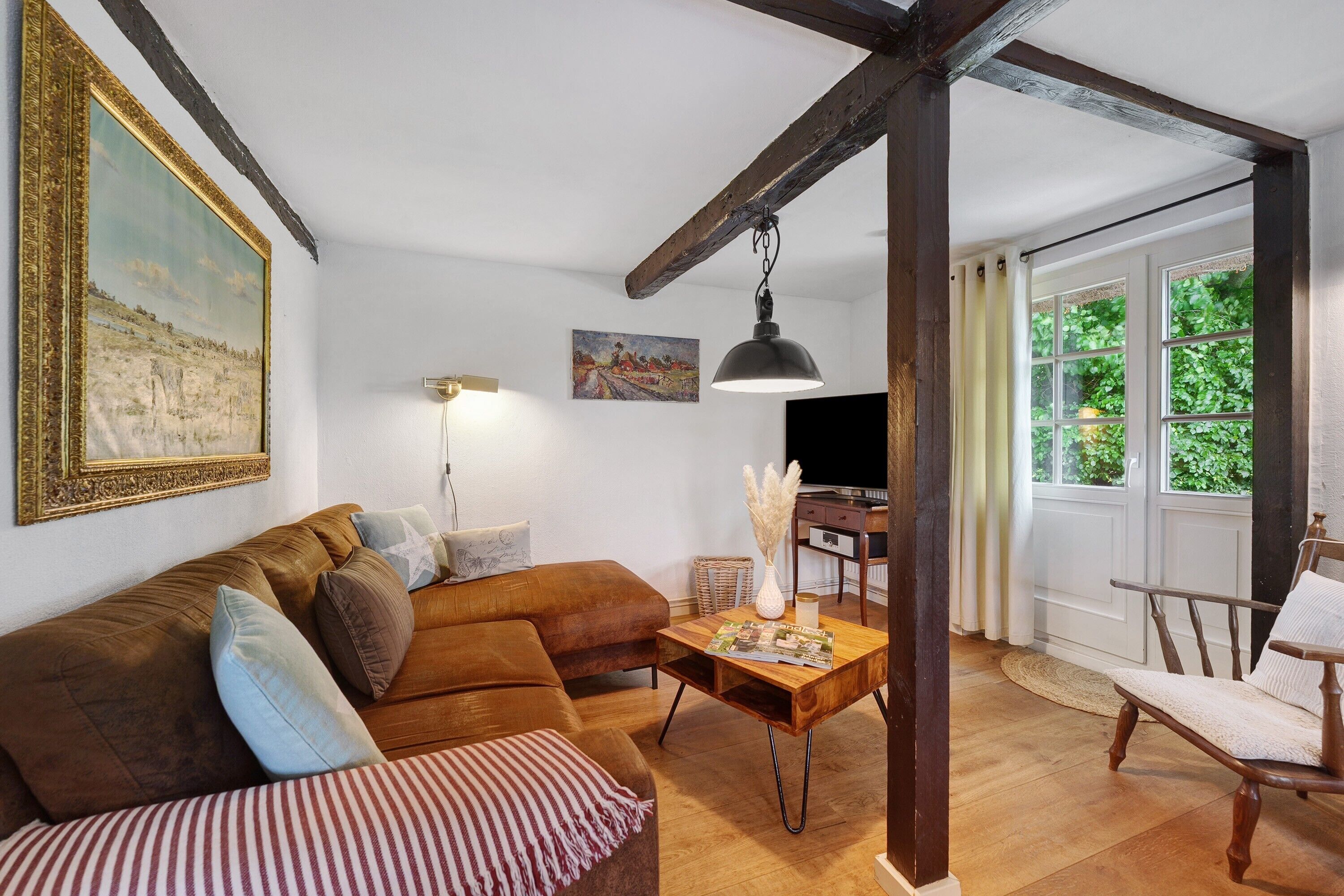 A living room with a sofa, a coffee table, a chair, a painting, and a television.