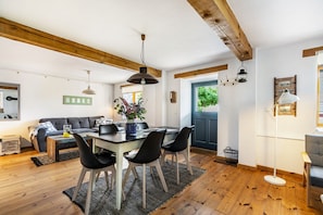 A dining area with a wooden table, black chairs, and a hanging pendant light.