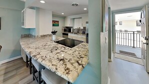 Una cocina moderna con encimeras de granito, estufa integrada y vistas al exterior.
