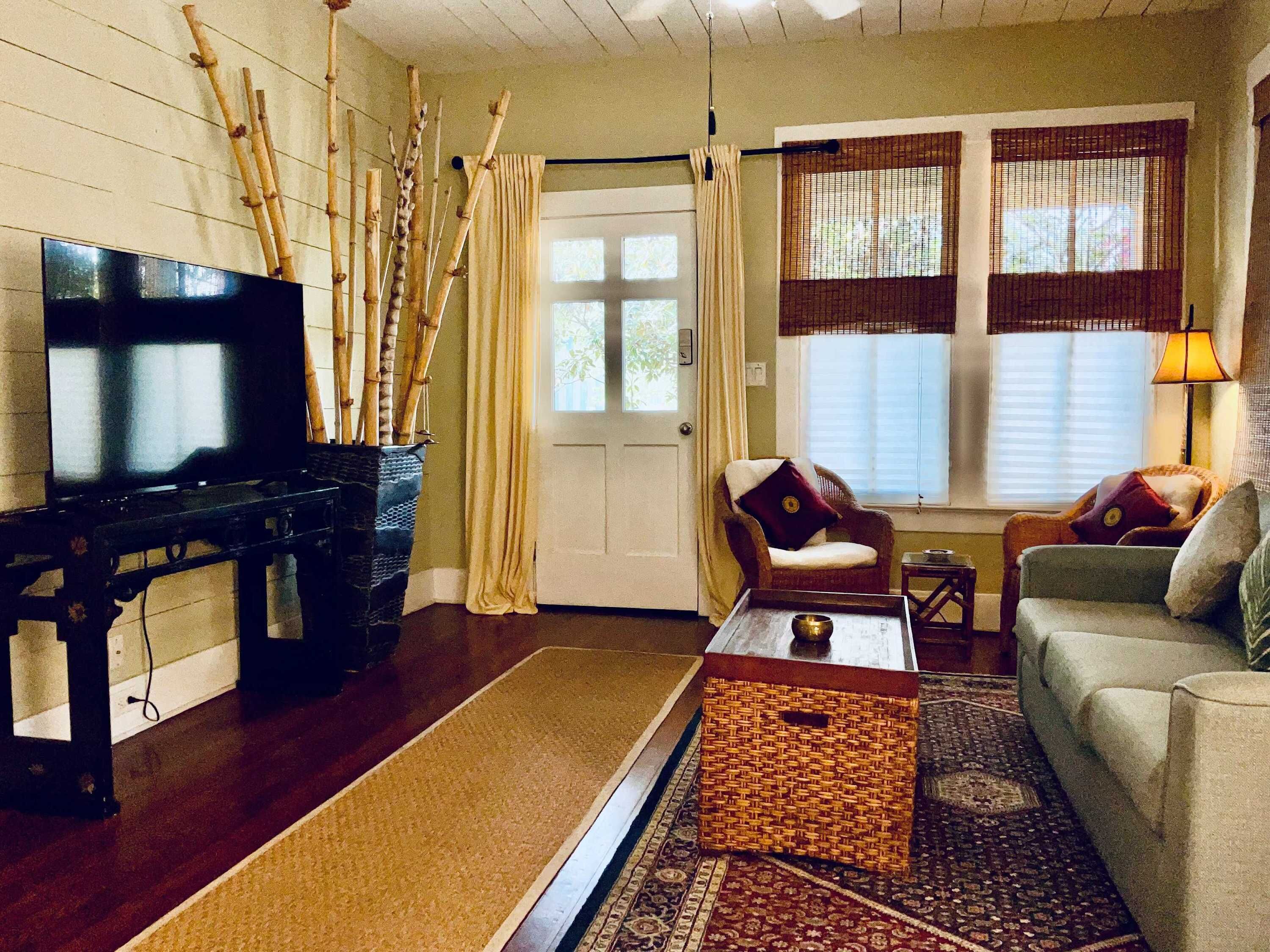 A living room with a piano, a sofa, a chair, a coffee table, and a window with blinds.