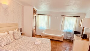 Een hotelkamer met een groot bed, een bank, een bijzettafeltje, een stoel en een kitchenette.