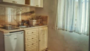 Een keuken met een inbouwvaatwasser, een spoelbak en een raam met lichte gordijnen.