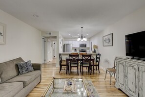 A modern living room with a sofa, a coffee table, and a TV. - Sunset Rentals | Moorings 71 | Dog Friendly (Hilton Head Island)