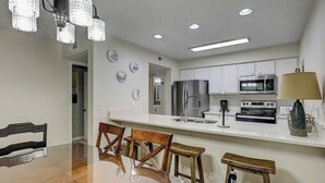 Una cocina moderna con electrodomésticos de acero inoxidable, un comedor con sillas de madera y una araña.