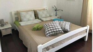 Een keurig opgemaakt slaapkamer met een bed, kussens, een nachtkastje, een wandklok en een motiverende quote.