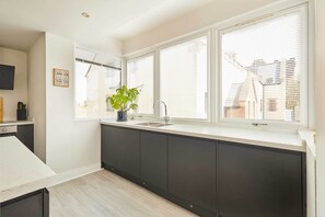 Una cocina moderna con un ventanal grande, armarios oscuros y una planta en maceta.