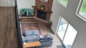 A spacious living area with a brick fireplace, a large sectional sofa, and a flat-screen TV.