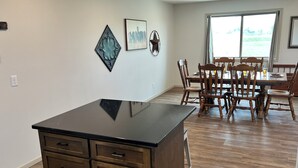 A modern kitchen with a black countertop, wooden cabinets, and a dining area with wooden chairs and a table.
