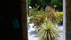 A stone archway leading to a garden with a large yucca plant and pink flowers. - TIPI TENT (Callen)