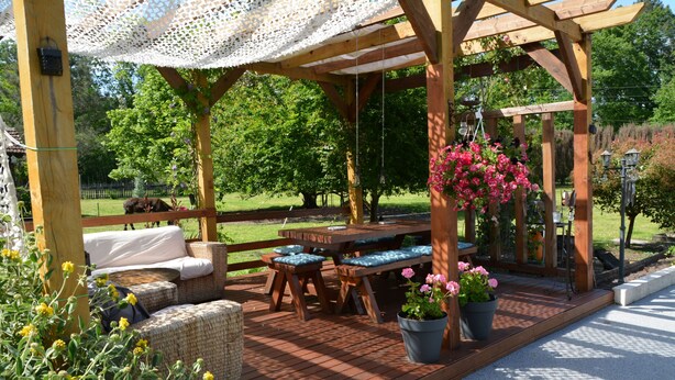 A wooden deck with outdoor furniture, a pergola, and potted plants. - TIPI TENT (Callen)